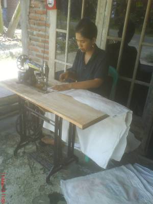 Yanti sedang merajut/menjahit kandi